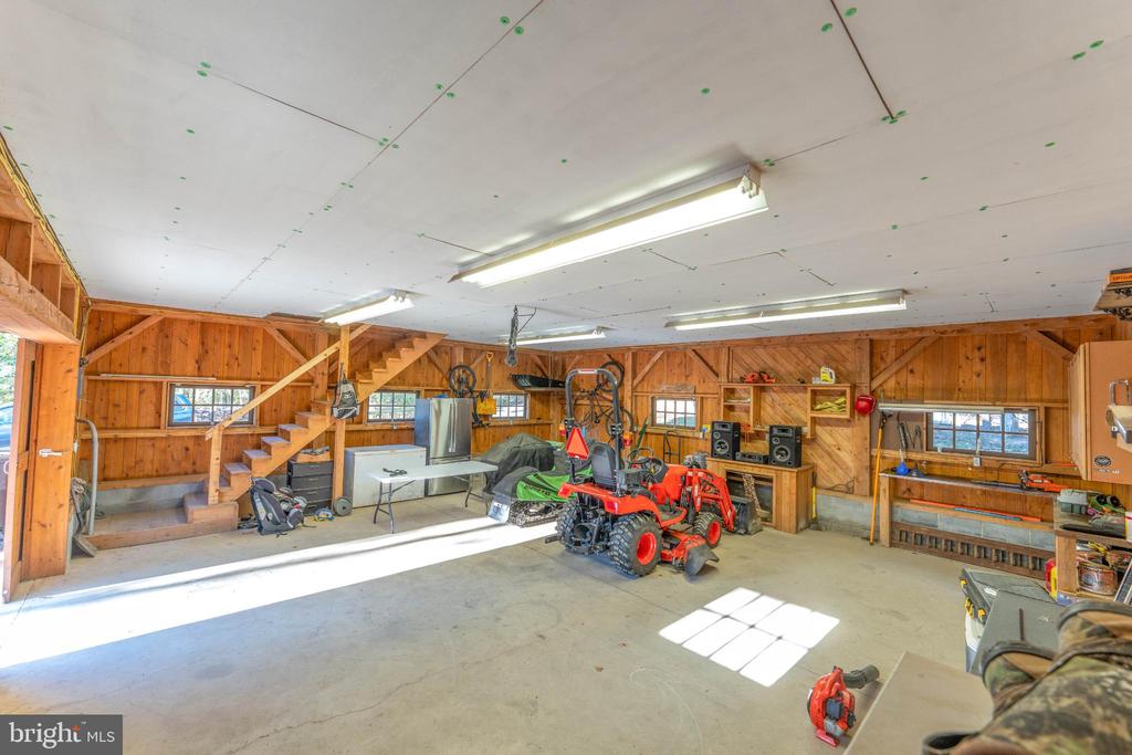 Wood-paneled garage with a staircase, work areas, and an orange utility tractor.