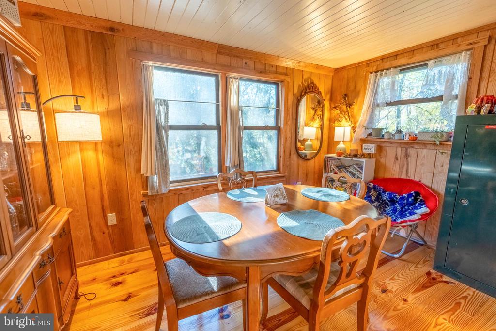 Wood-paneled dining room with a round table, matching chairs, and windows.