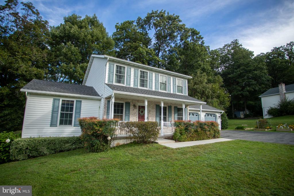 Two-story white house with pale blue shutters, a covered porch, and attached garage.