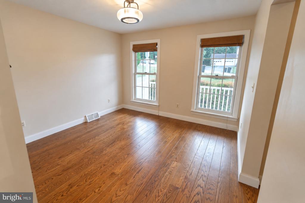 Empty room with hardwood floors, two windows with wooden blinds, and a ceiling light.