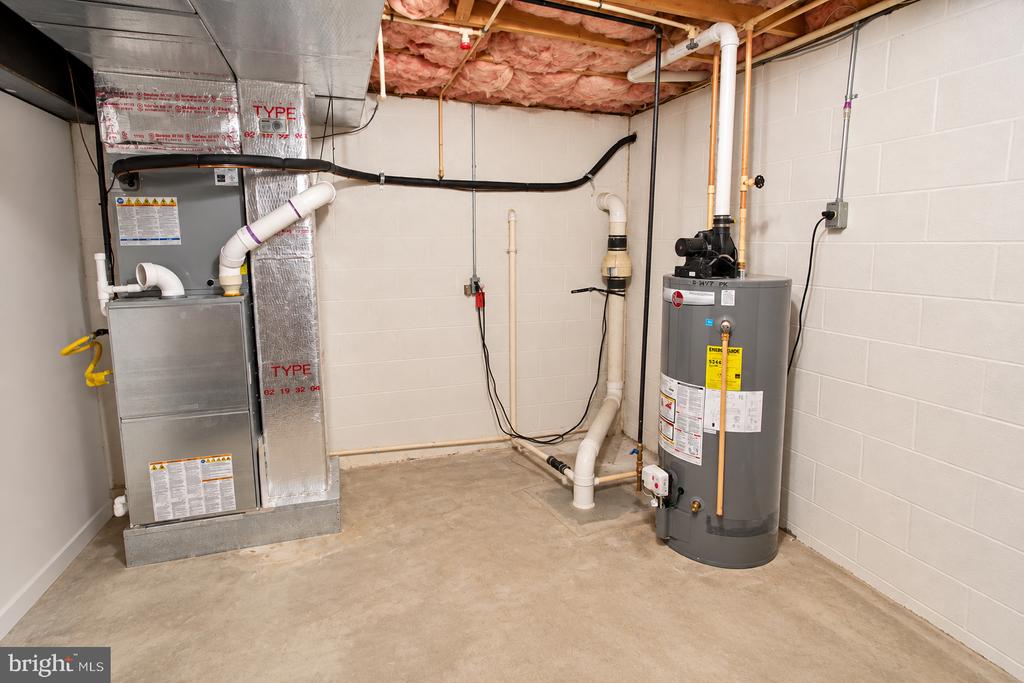 Basement utility room with furnace and water heater beneath exposed ceiling insulation.