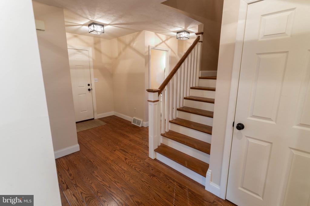 Foyer with polished hardwood floors and a staircase with dark wood treads and handrail.