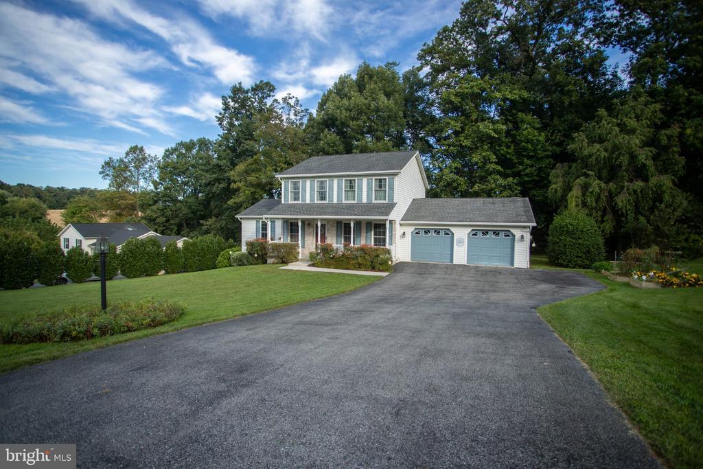 Two-story white house with blue shutters, a covered porch, and a curved driveway.