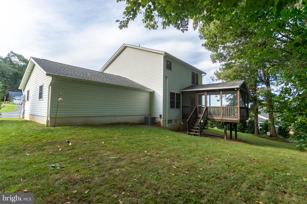 House with a raised screened porch and mature trees behind it.