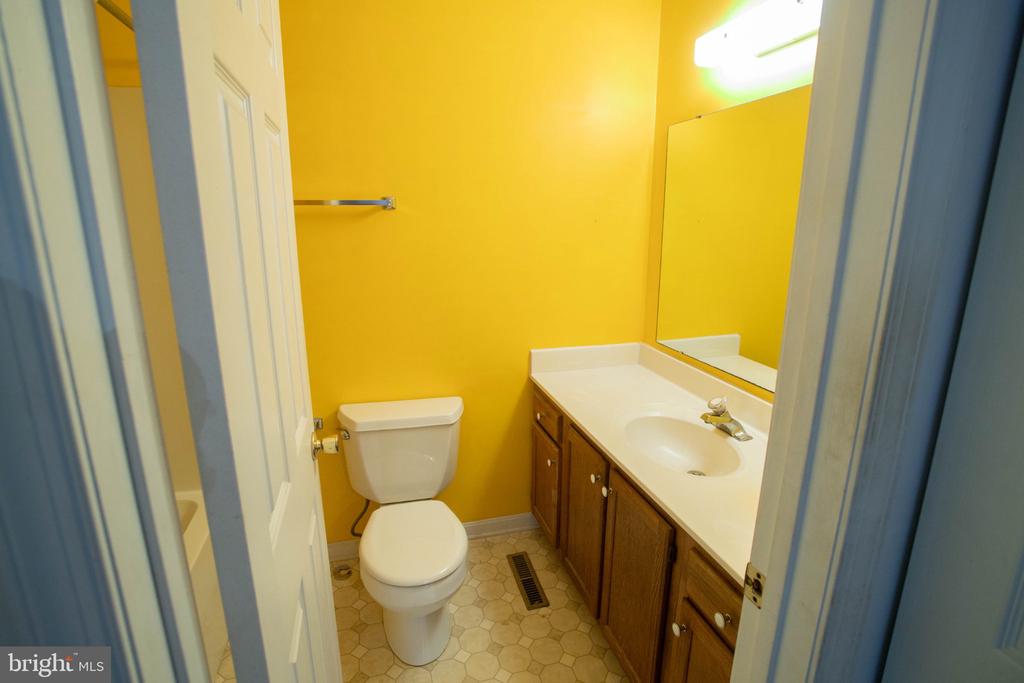 Bathroom with bright yellow walls, a wood vanity, large mirror, and hexagonal tile floor.
