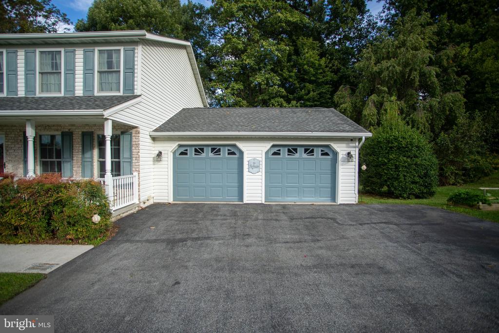 House exterior with an attached two-car garage, blue doors, and a broad asphalt driveway.