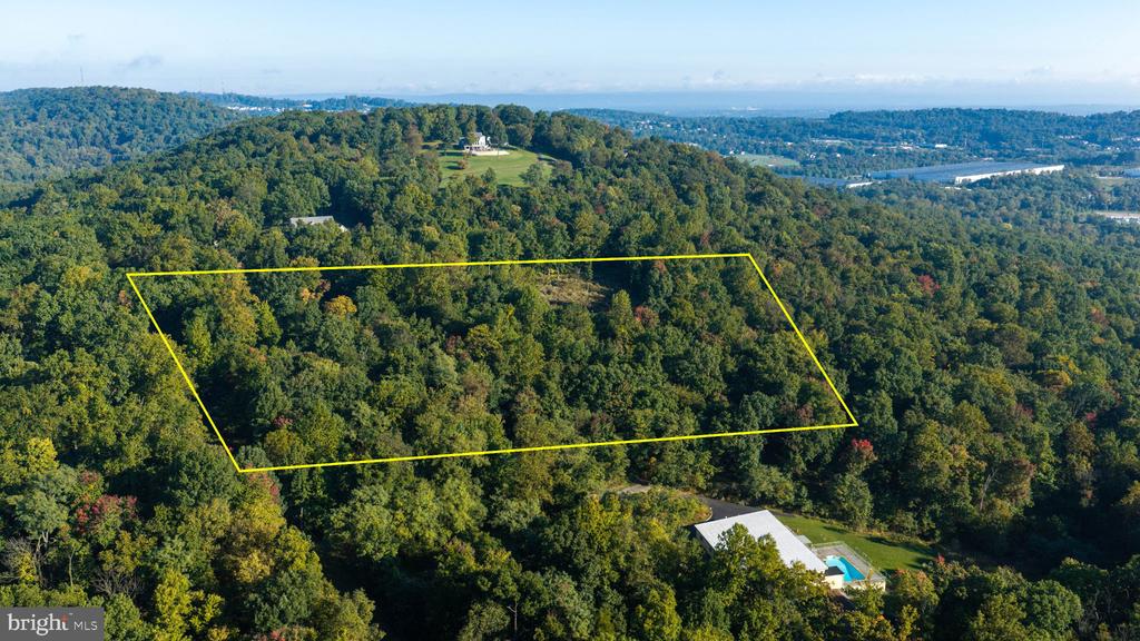 Aerial view of a wooded parcel outlined in yellow amid rolling forested hills.