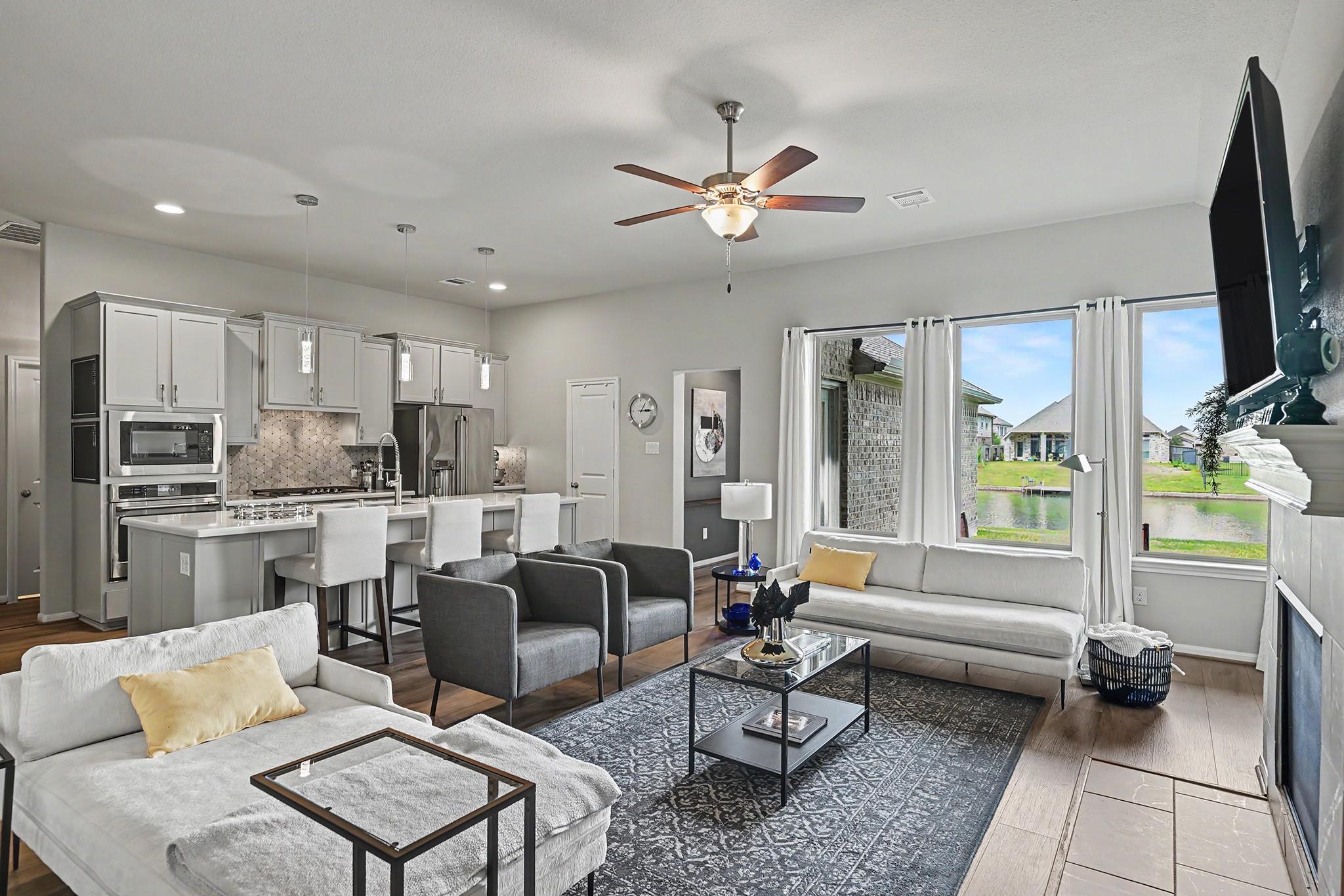 Open-plan living room and kitchen with gray cabinetry, a furnished sitting area, and canal views through wide windows.