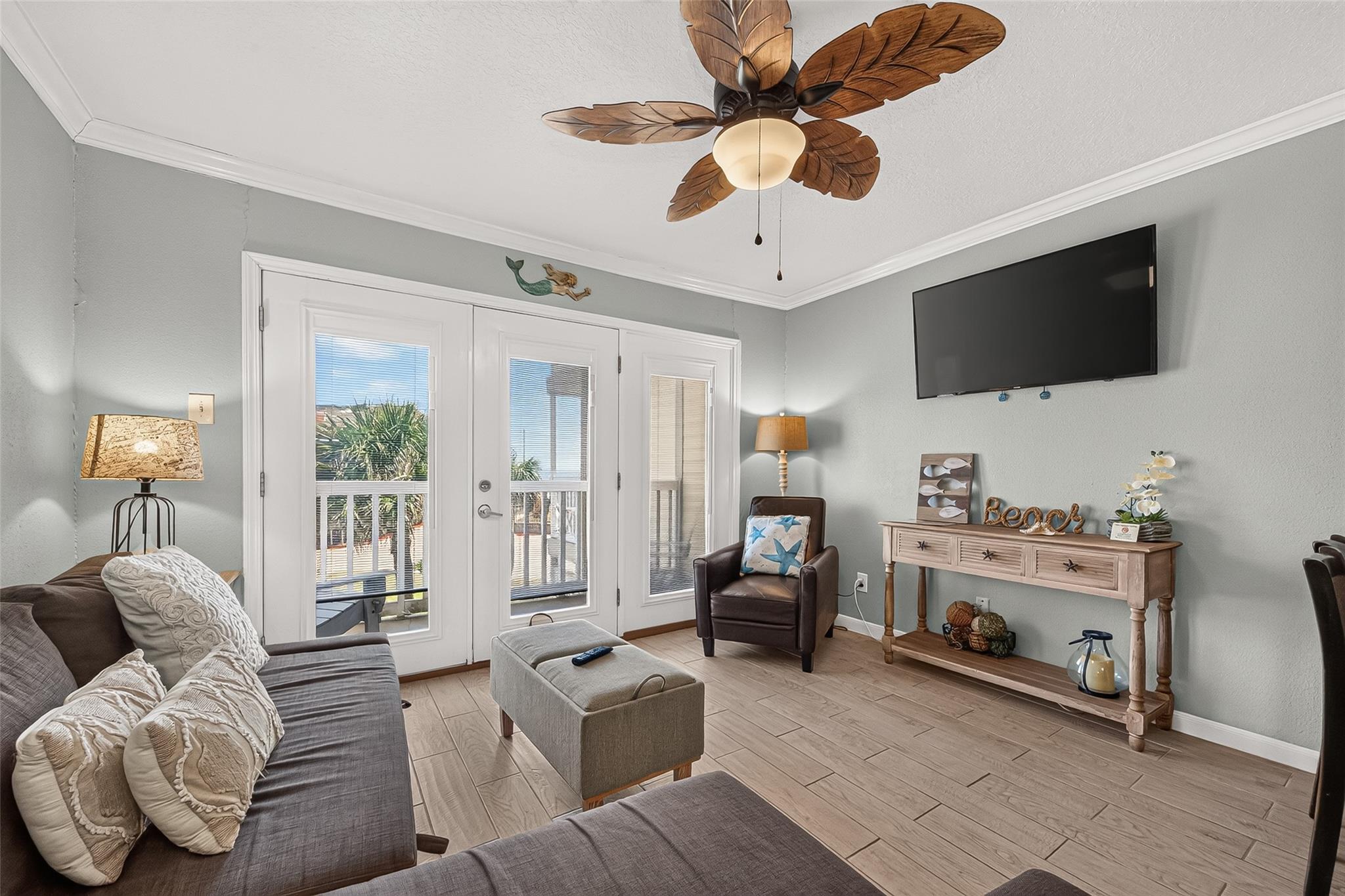Living room with a leaf-shaped ceiling fan and glass doors opening to a balcony.