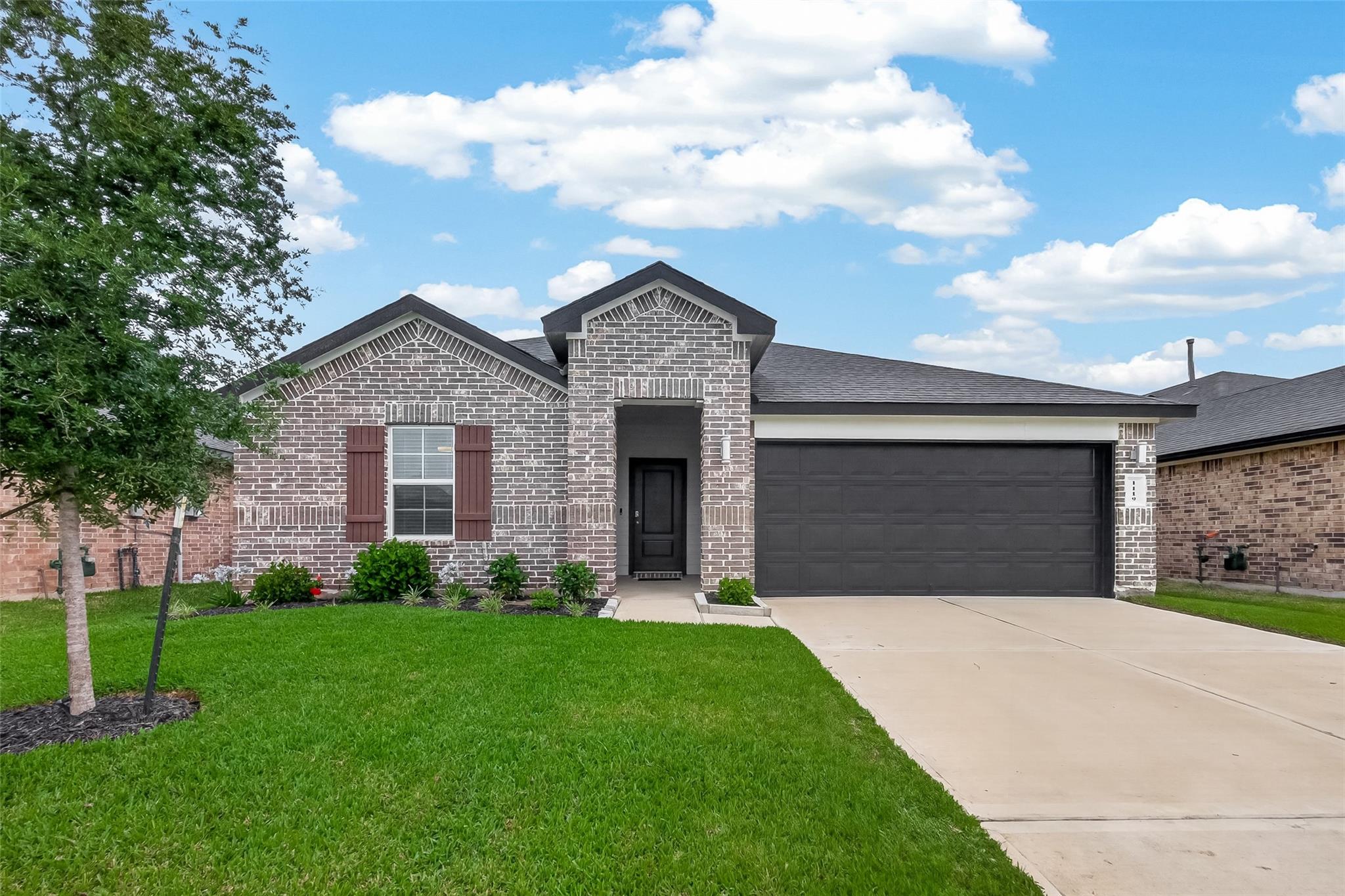 Brick house with a recessed entry, wide garage, driveway, and green front lawn.