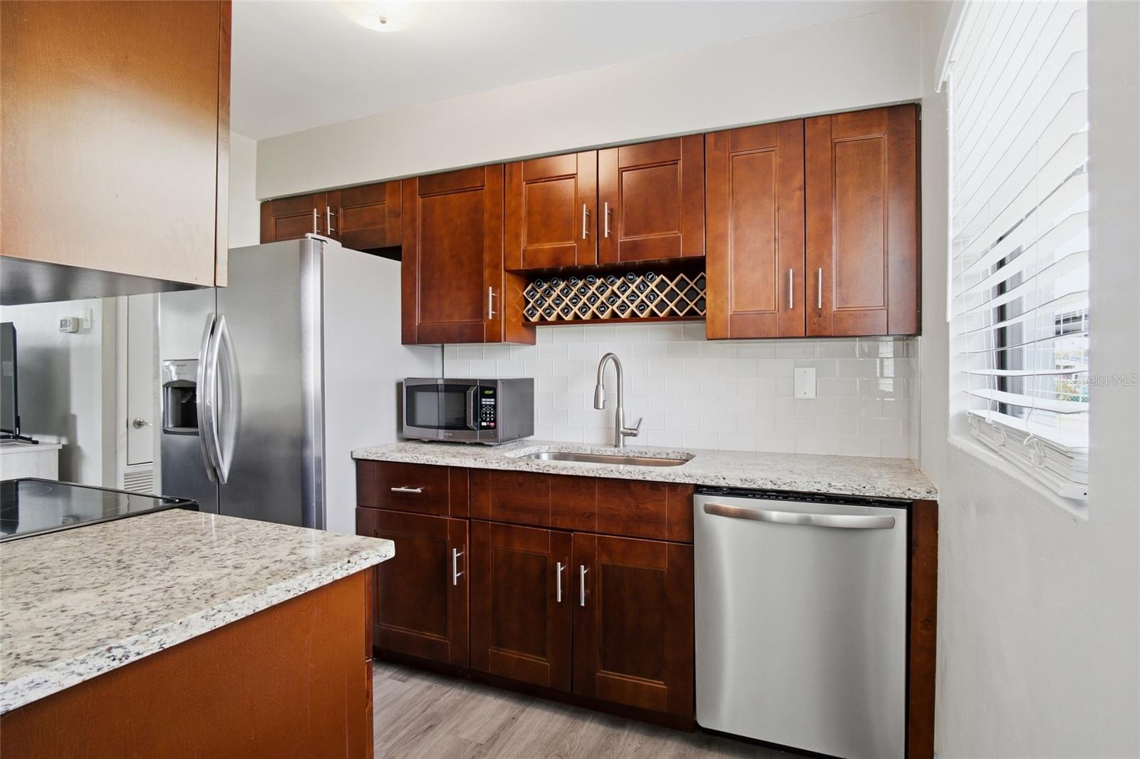 Kitchen with dark wood cabinets, granite counters, stainless appliances, and a built-in wine rack.
