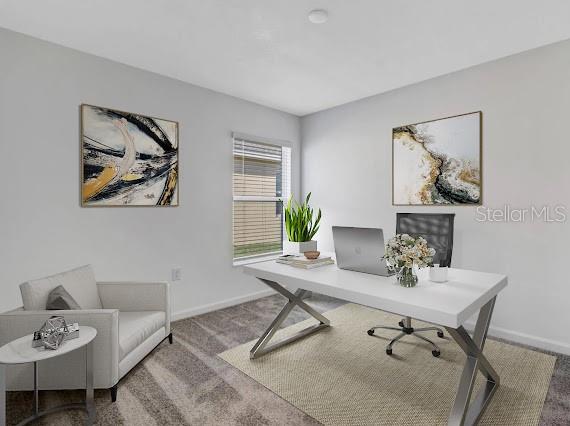 Home office with a white desk, computer, and small sofa beside a window.
