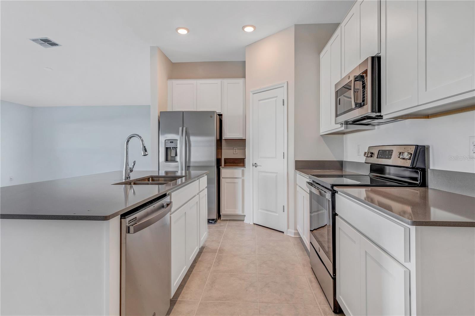 Modern kitchen with white cabinetry, stainless steel appliances, and an island sink.