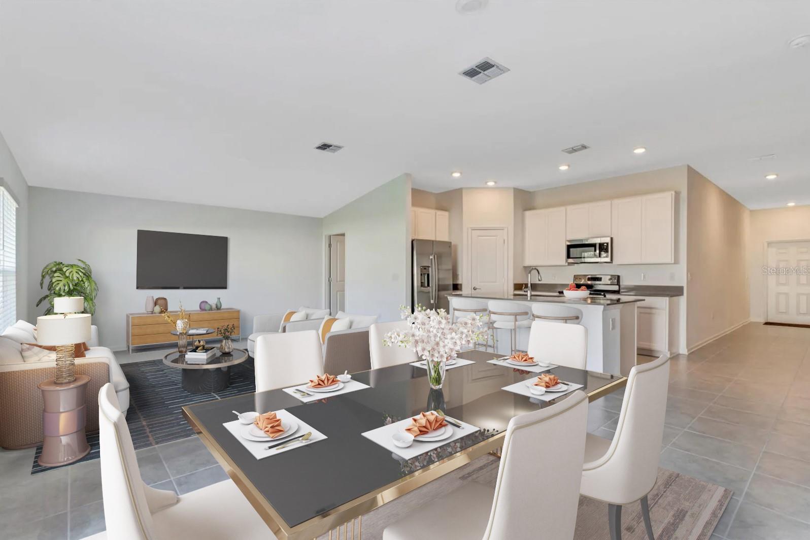 Open-plan kitchen and dining area with a central island and staged table beside the living room.
