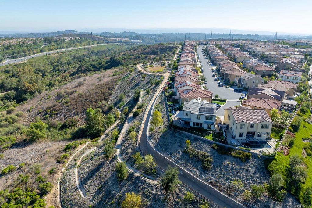 Aerial view of homes beside undeveloped green space, with a map pin marking one house.