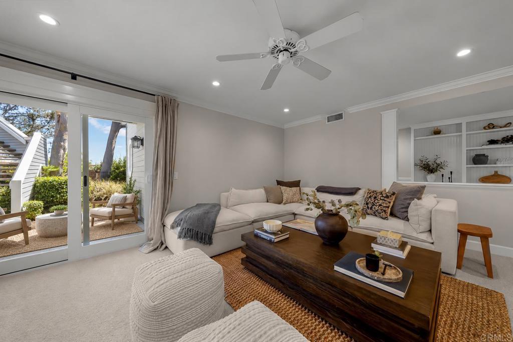 Staged living room with a white sectional, dark wood coffee table, and sliding doors to a leafy patio.