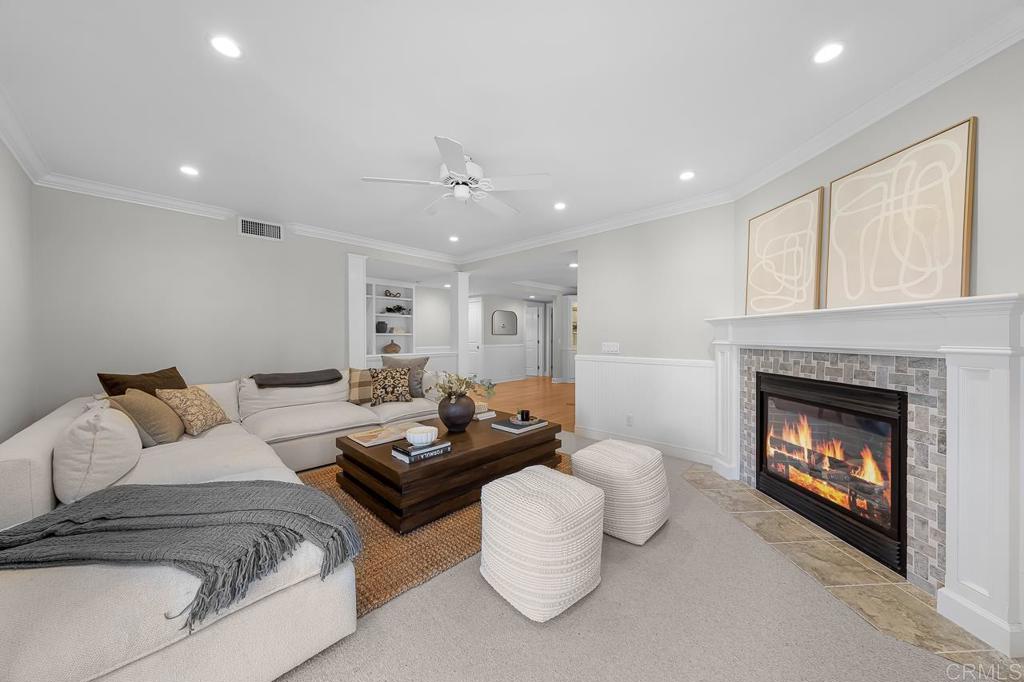 Living room with a white sectional, round ottomans, and a lit fireplace.