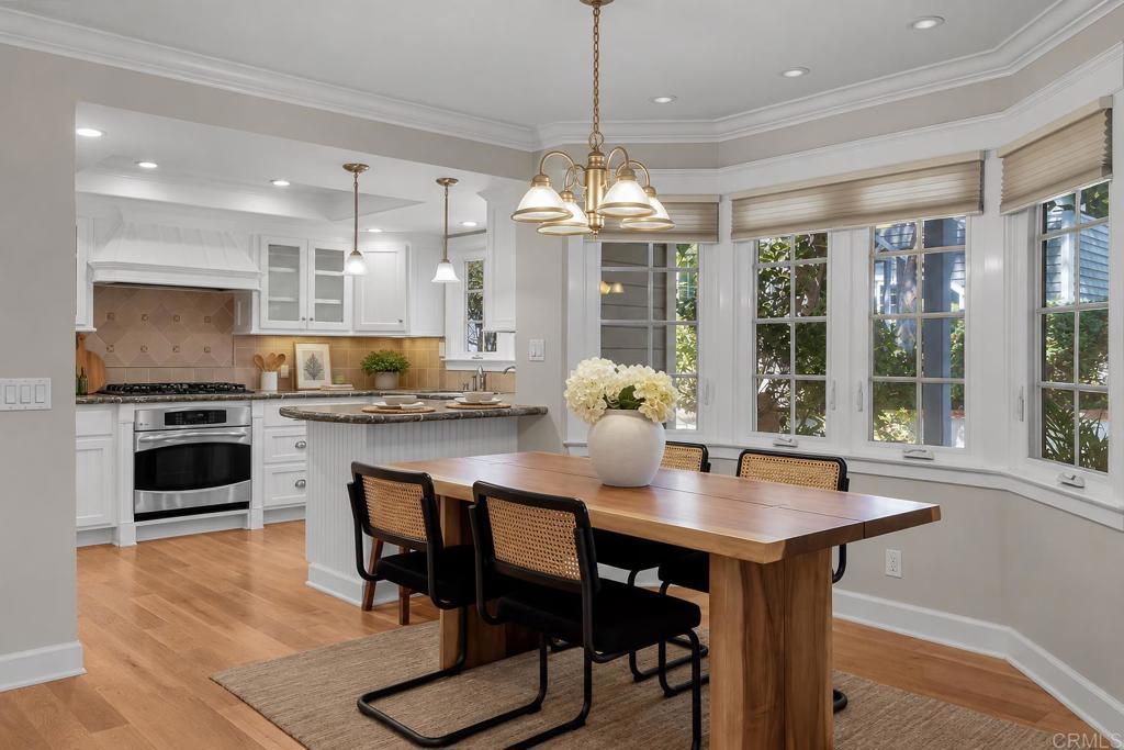Kitchen and dining area with a large wood table, bay windows, and white cabinetry.