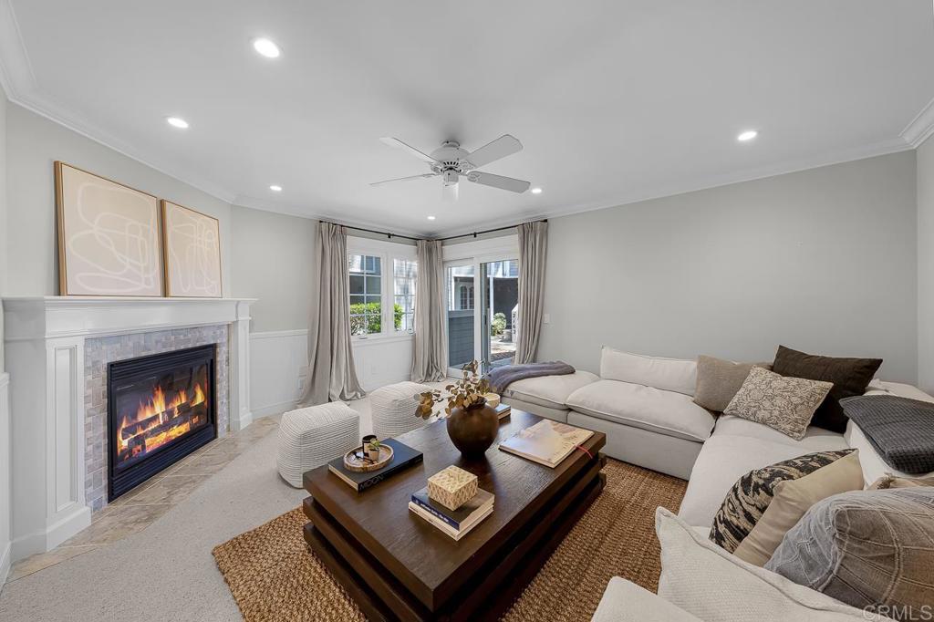 Staged living room with a white sectional, dark wood coffee table, and lit fireplace.