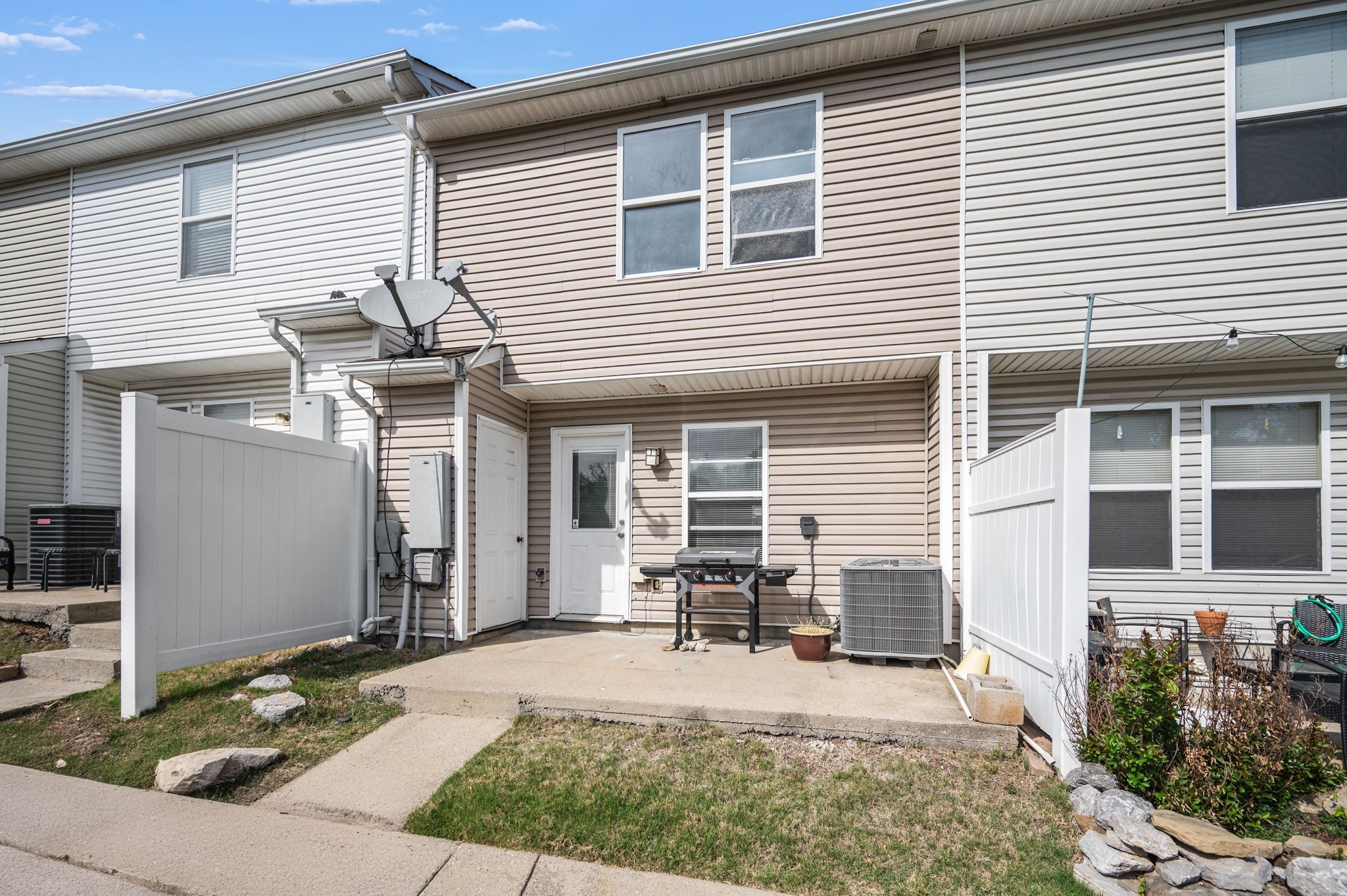 Townhouse rear patio with white privacy fencing and a gas grill.