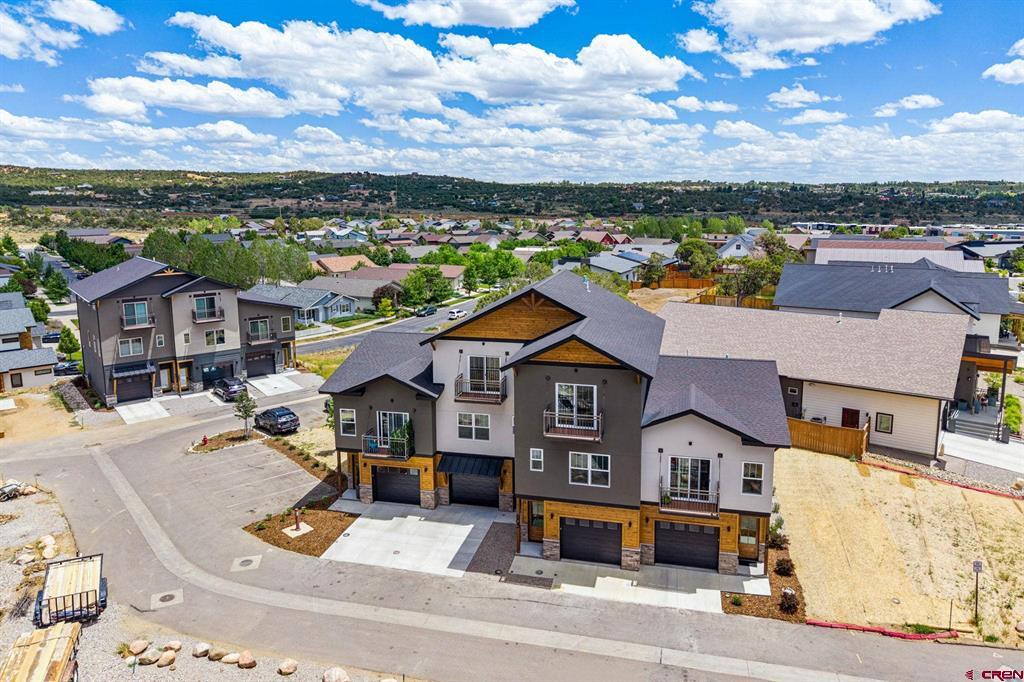Aerial view of modern townhomes along a residential street, with Durango-area neighborhoods and hills beyond.