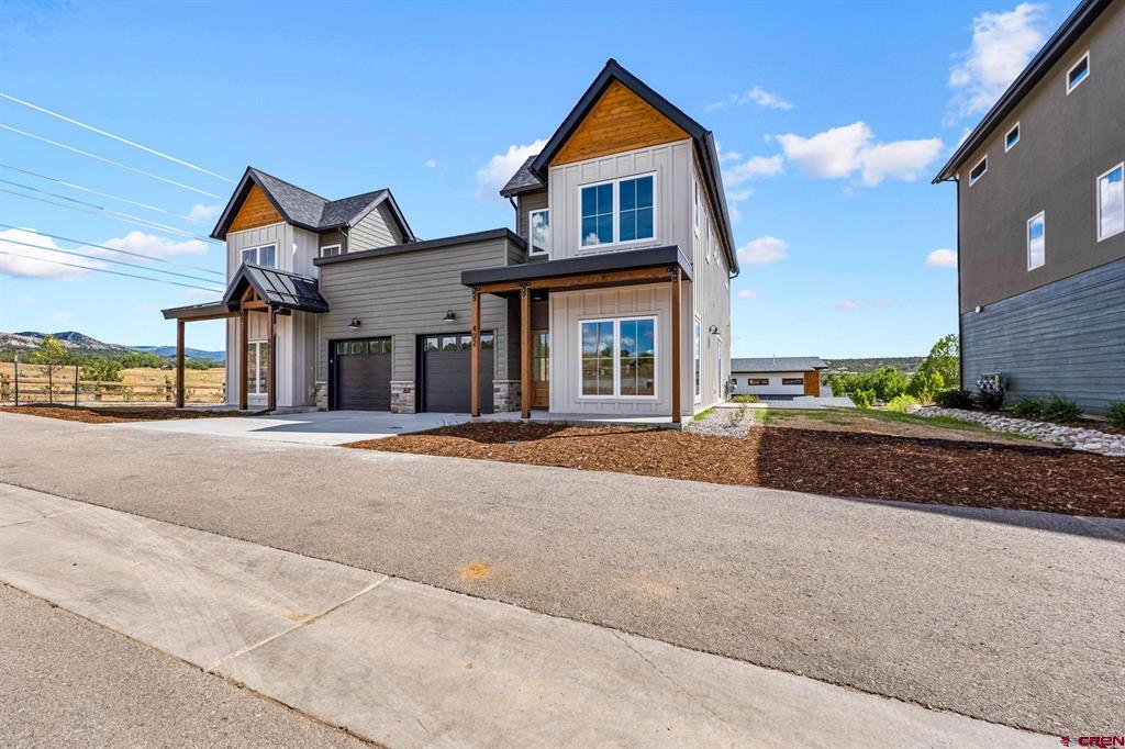 Modern two-story home with gray siding, front-facing gables, and an attached two-car garage.