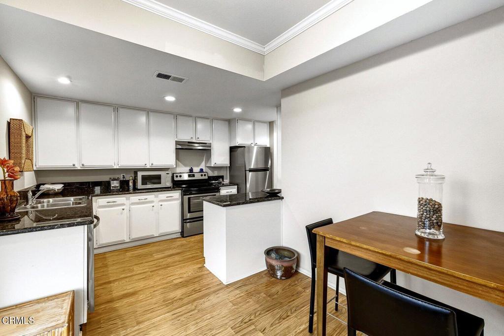 Kitchen with white cabinets, stainless steel appliances, and a wood dining table with black chairs.
