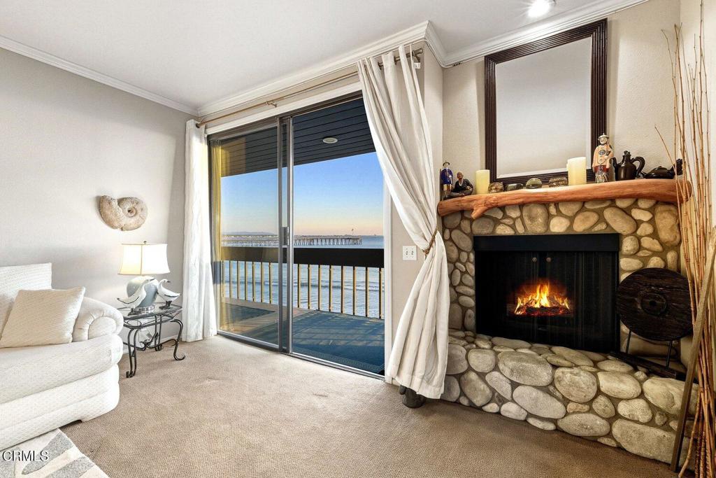 Living room with a stone fireplace and sliding doors overlooking the water and a pier.