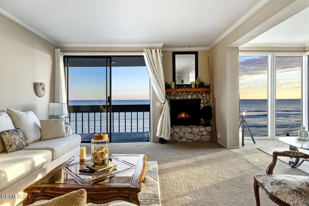 Oceanfront living room with stone fireplace, white sofa, and expansive ocean-view windows.