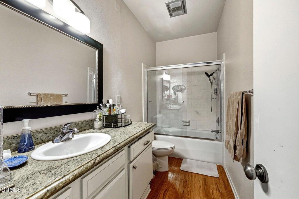 Bathroom with granite vanity, framed mirror, and glass-enclosed tub and shower.