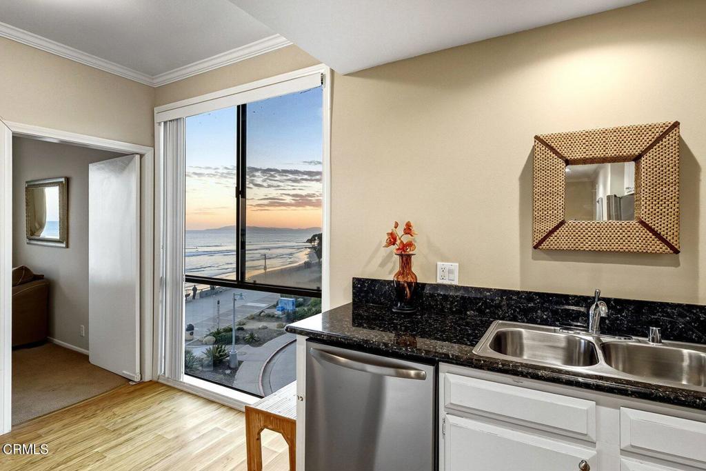 Kitchen with a double sink and granite counters overlooking the ocean at sunset.