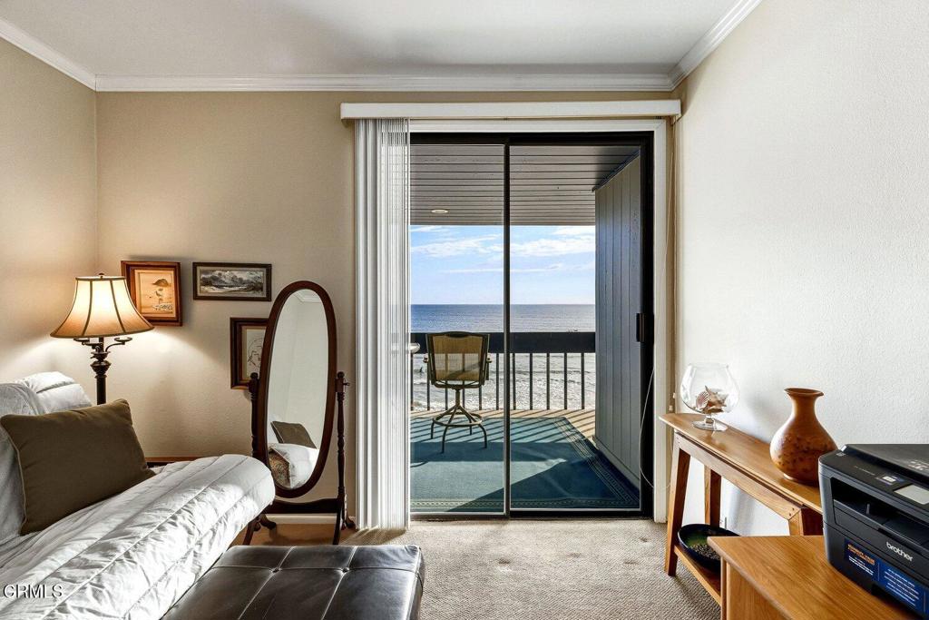Furnished living room opening onto a balcony with a chair and ocean view.