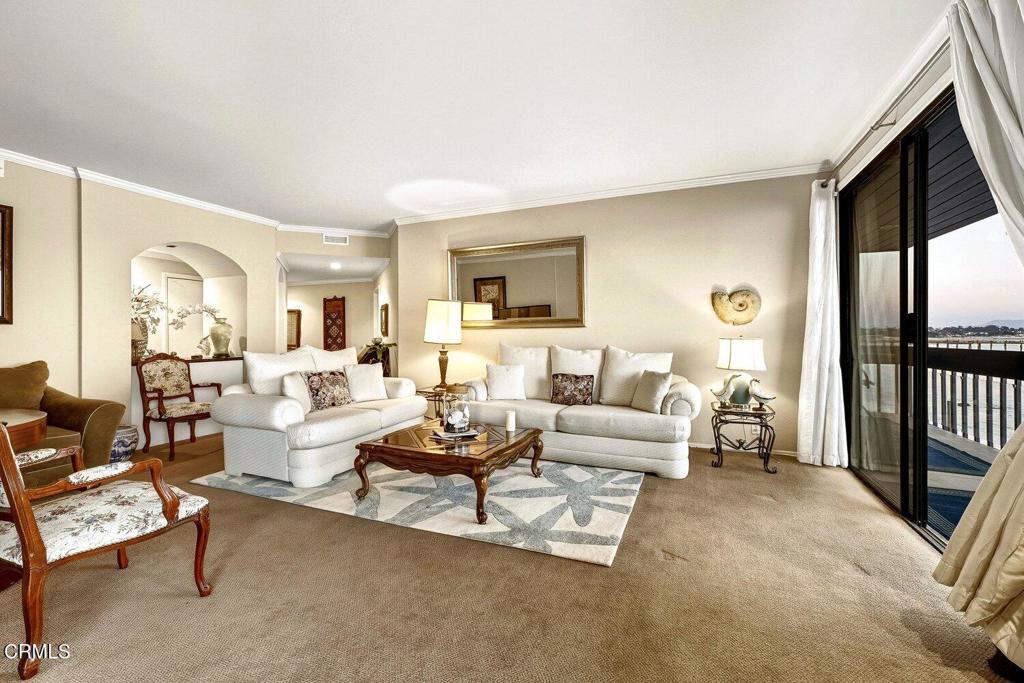 Living room with white sofas and a balcony overlooking the water.
