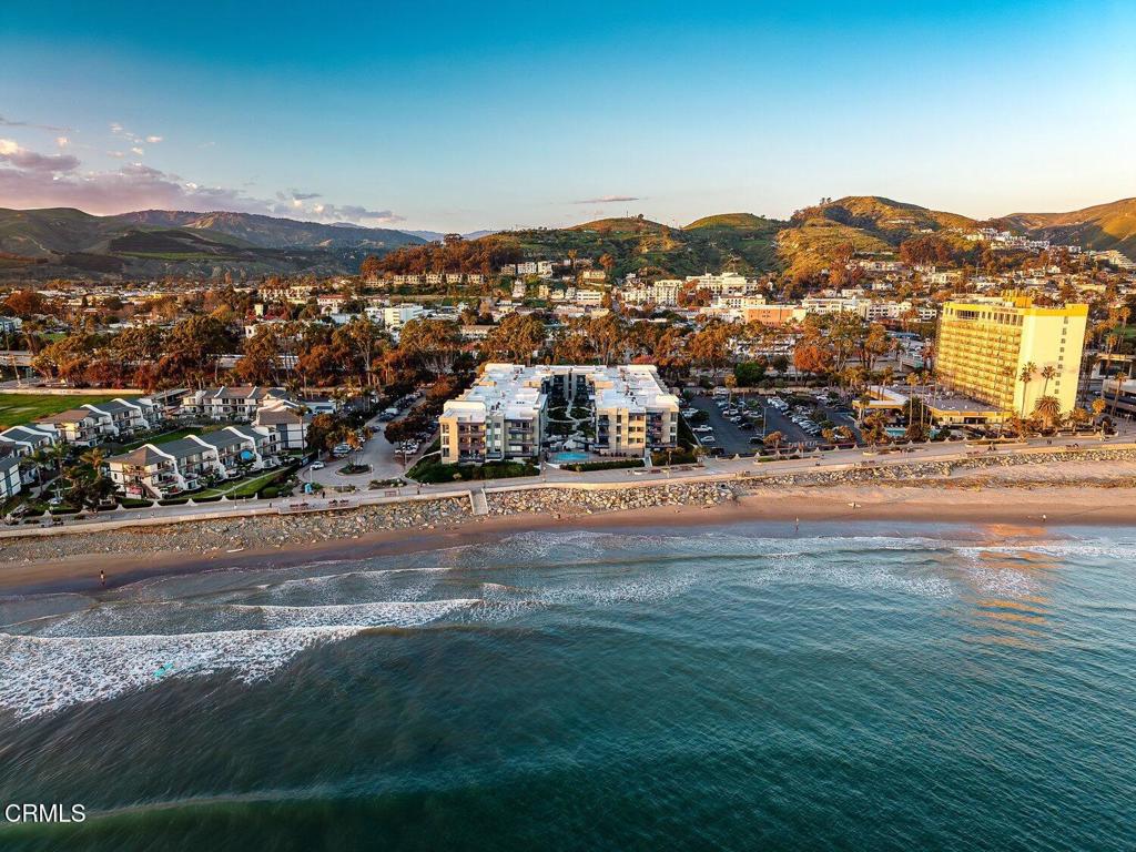 Aerial view of Ventura coastline, beachfront residences, ocean, and hills at golden hour.