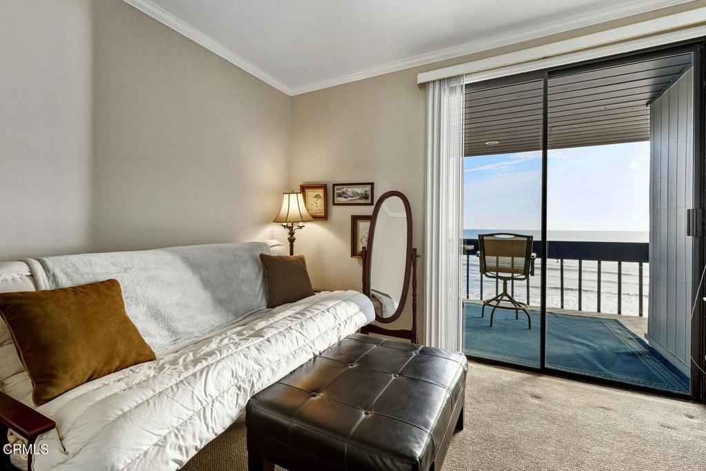 Living room with a white-covered sofa and sliding doors opening to an ocean-view balcony.