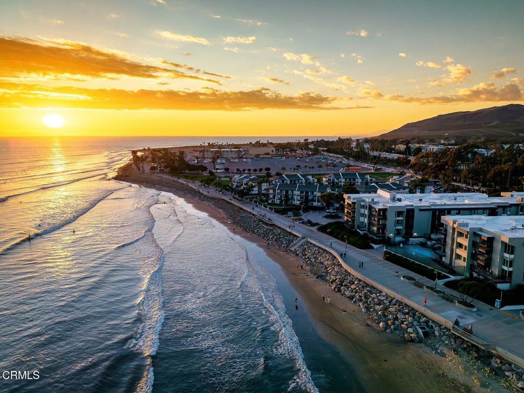 Aerial view of the coastline, beach, and beachfront buildings at sunset.
