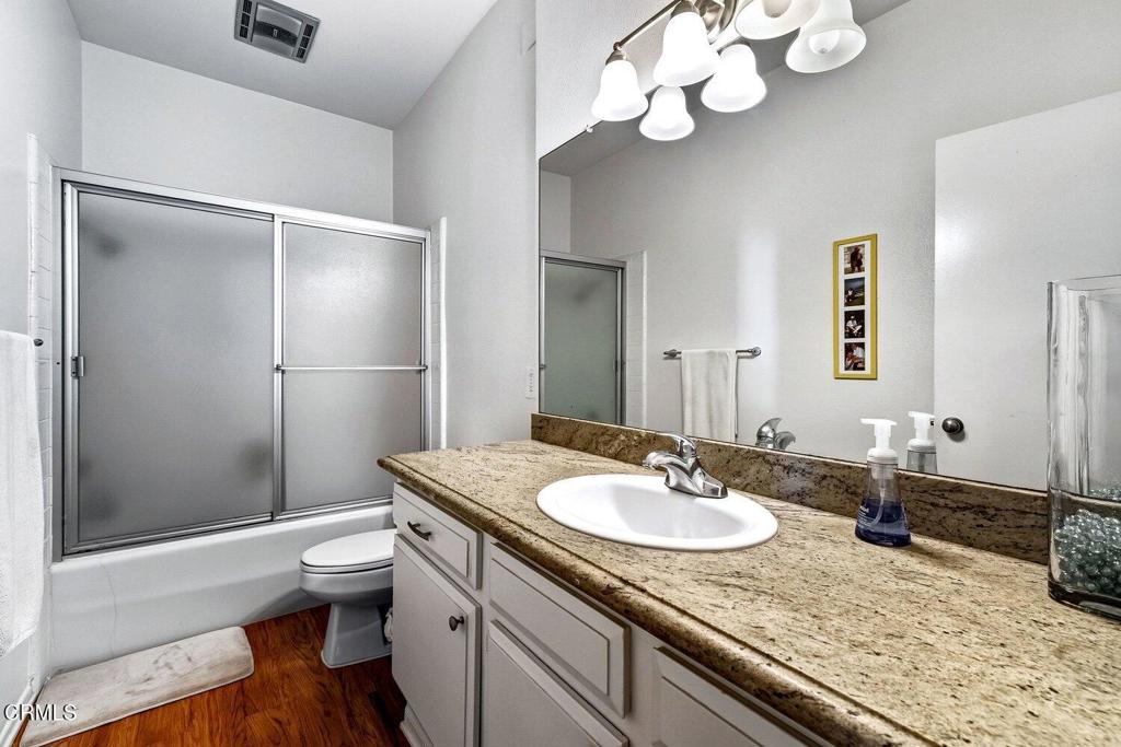 Bathroom with granite vanity, oval sink, and frosted sliding shower doors.