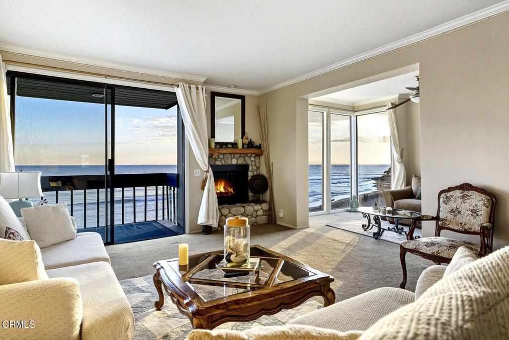 Oceanfront living room with a stone fireplace and windows overlooking the water.