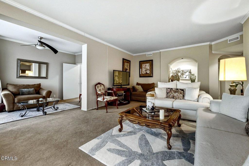 Living room with white sofas, patterned rugs, and an adjoining sitting area.