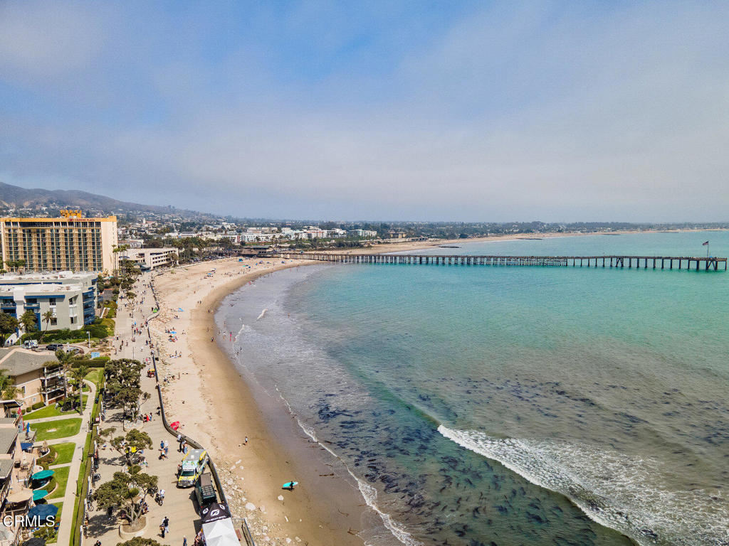 Aerial view of Ventura beach, turquoise water, a long pier, and coastal hills.