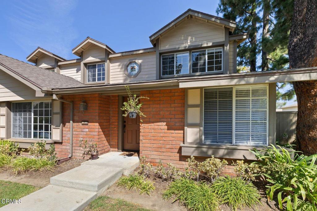 Two-story home with a red brick facade, gabled dormers, and a landscaped front entry.