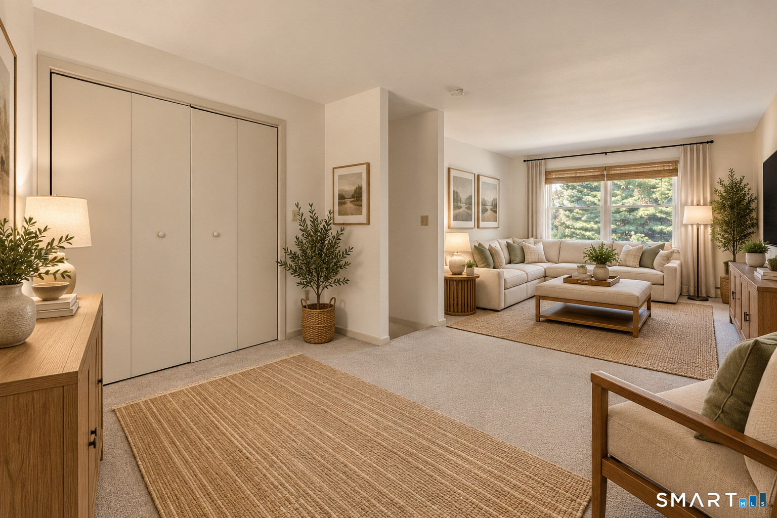 Living room with a cream sectional sofa, large sunlit window, woven shades, and wide closet doors.