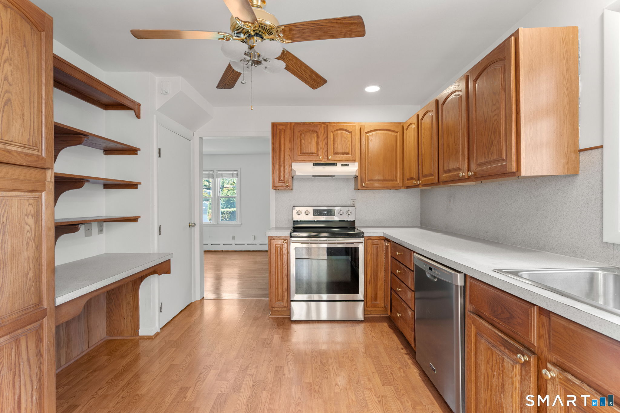 Kitchen with warm wood cabinetry, open shelving, and stainless steel appliances.