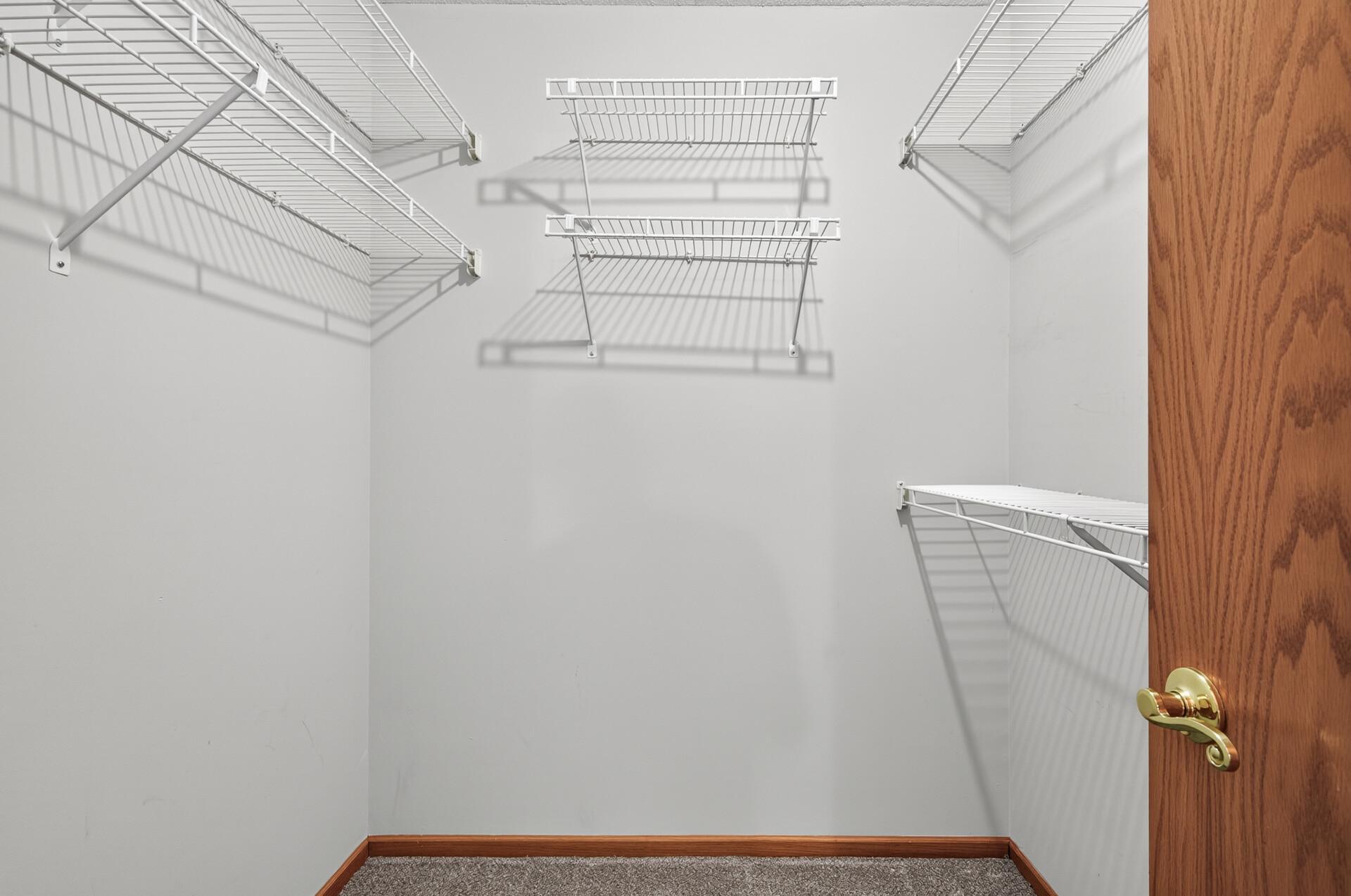 Walk-in closet with wire shelving, gray carpet, and an open wood door.