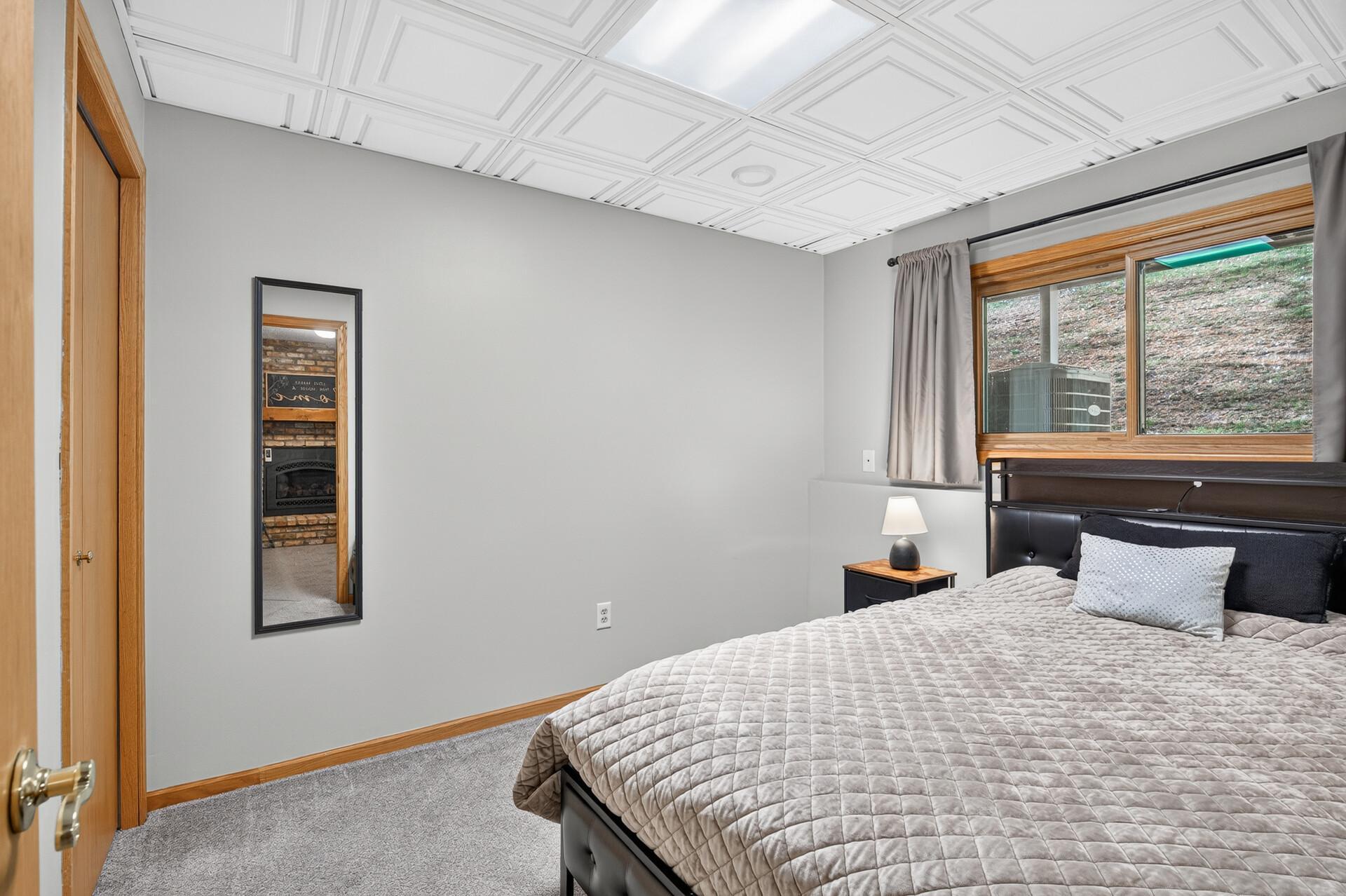 Bedroom with a quilted bed and decorative white patterned ceiling.