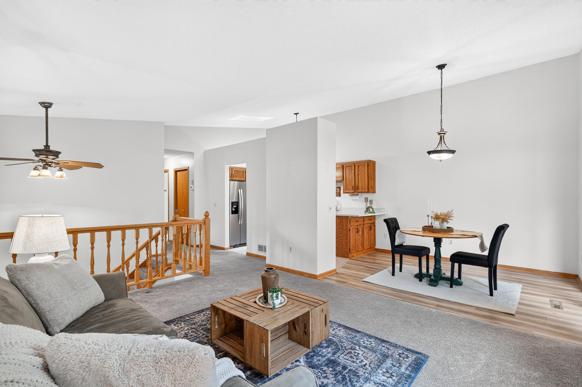 Open-plan living and dining area with oak kitchen cabinets and a carpeted stair landing.