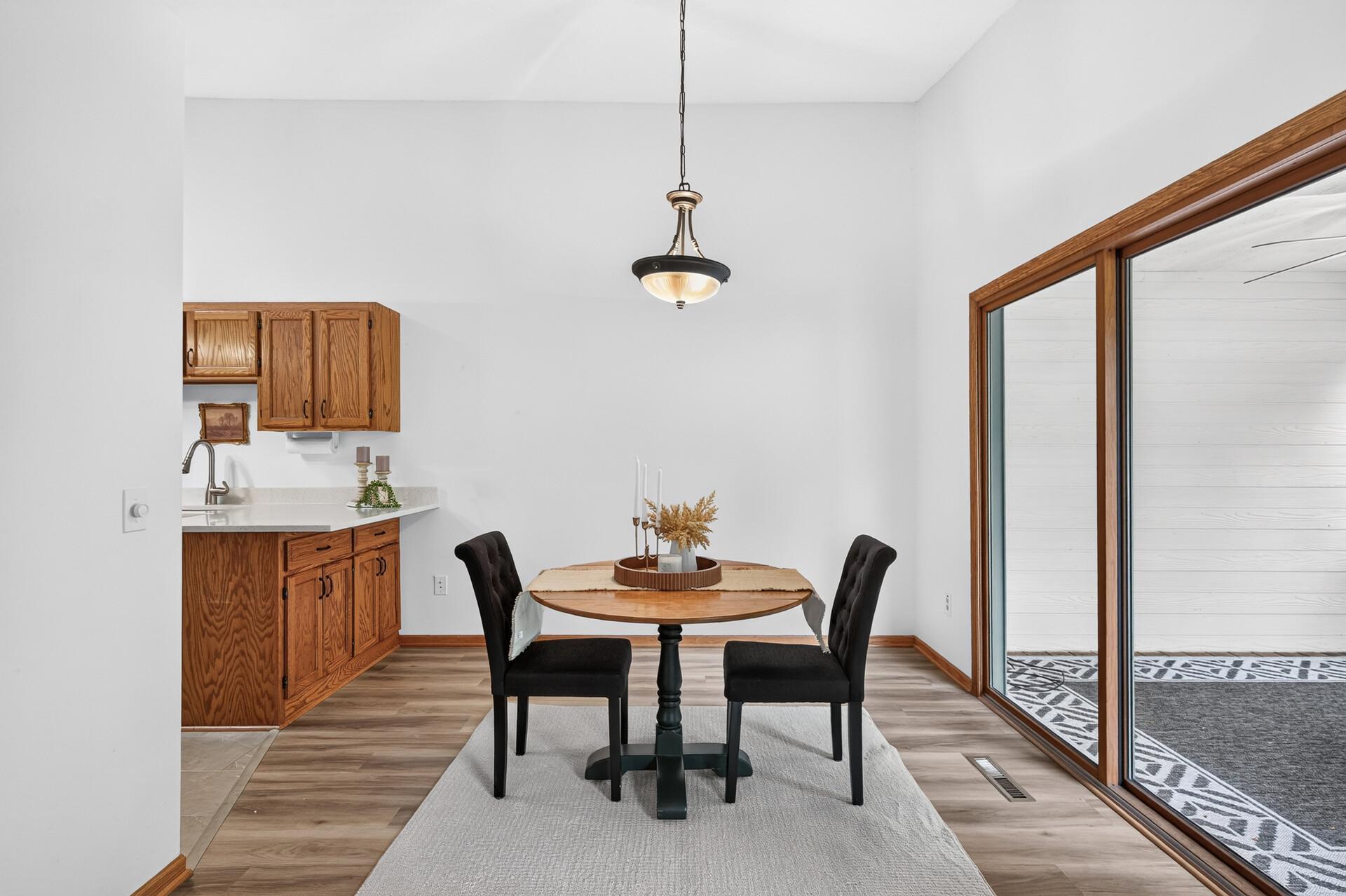 Dining area with a round wood table, black chairs, and sliding glass doors to a sunroom.