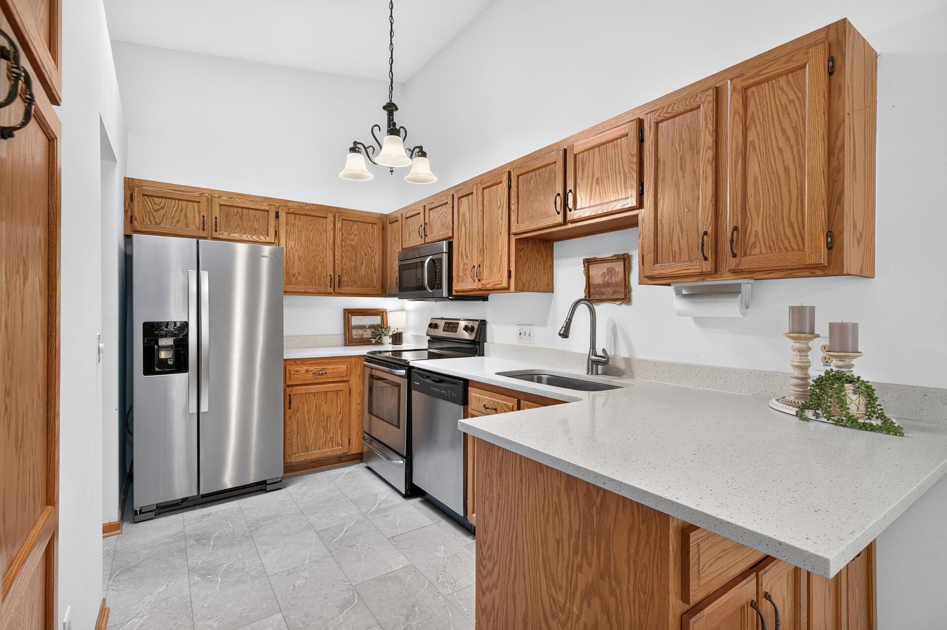 Kitchen with oak cabinets, stainless steel appliances, and a large peninsula with a double-basin sink.