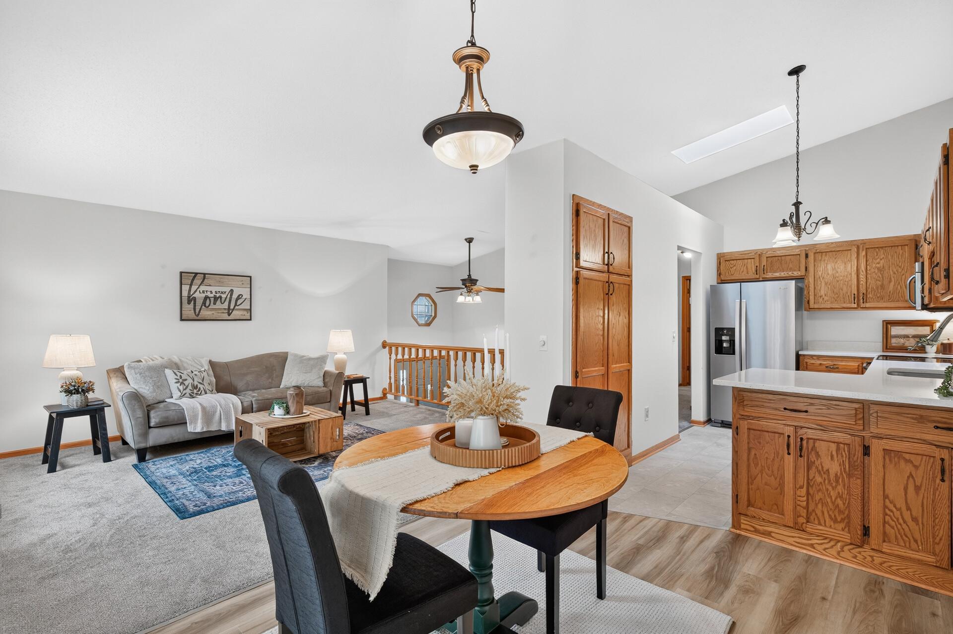 Open-plan living room and kitchen with a gray sofa, oak cabinetry, and a round wood dining table.