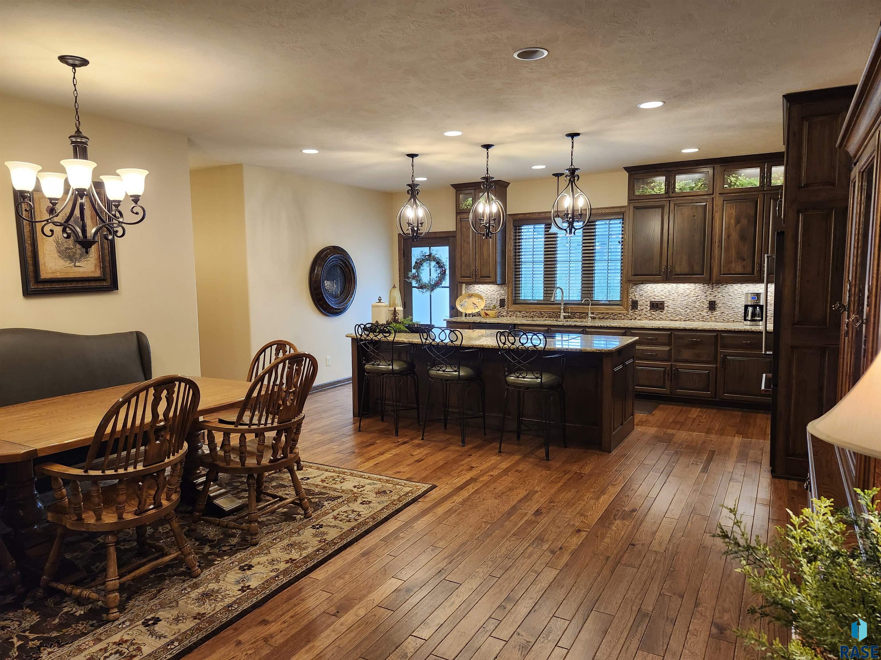 Kitchen and dining area with dark wood cabinetry, a large island, and hardwood floors.